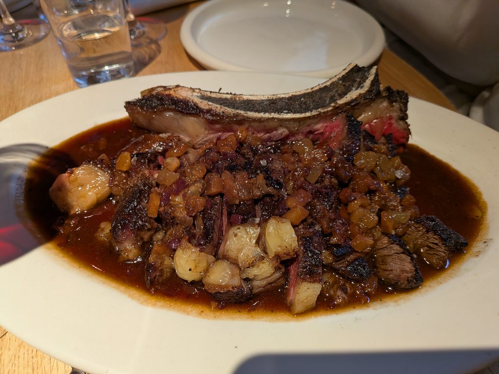 Beef wing-rib with a pile of lardo and shallot pieces on top, with lots of sauce/gravy